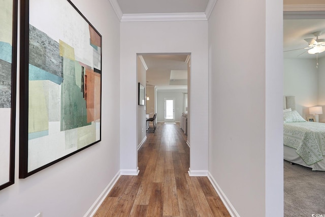 hallway with crown molding, baseboards, and wood finished floors