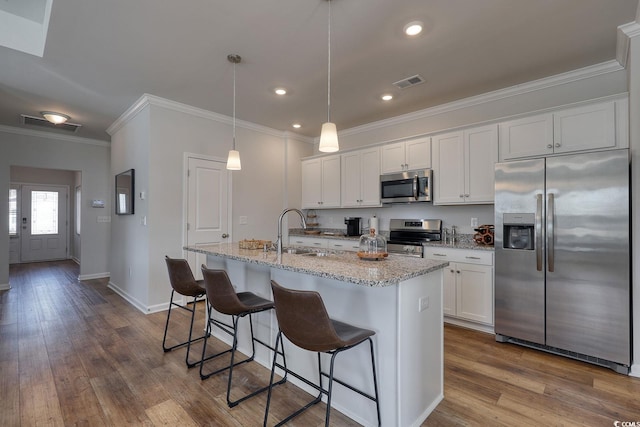 kitchen featuring stainless steel appliances, visible vents, white cabinets, and ornamental molding
