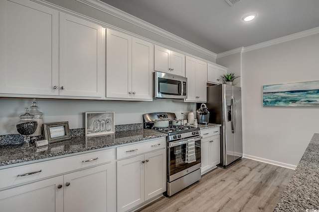 kitchen featuring white cabinetry, ornamental molding, appliances with stainless steel finishes, and dark stone counters