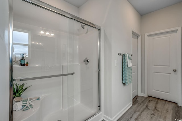 bathroom with a shower with shower door and hardwood / wood-style floors