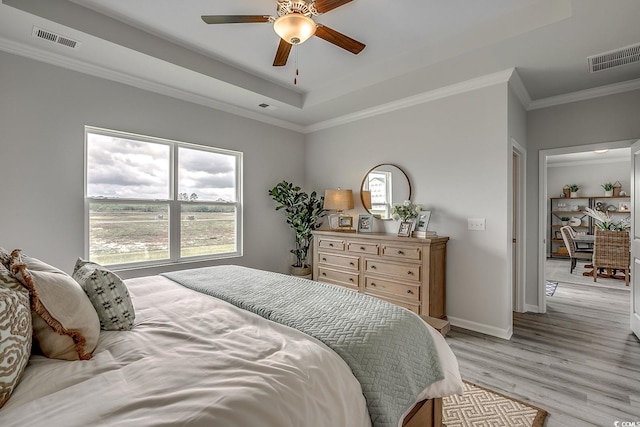 bedroom featuring a raised ceiling, ornamental molding, ceiling fan, and light hardwood / wood-style floors