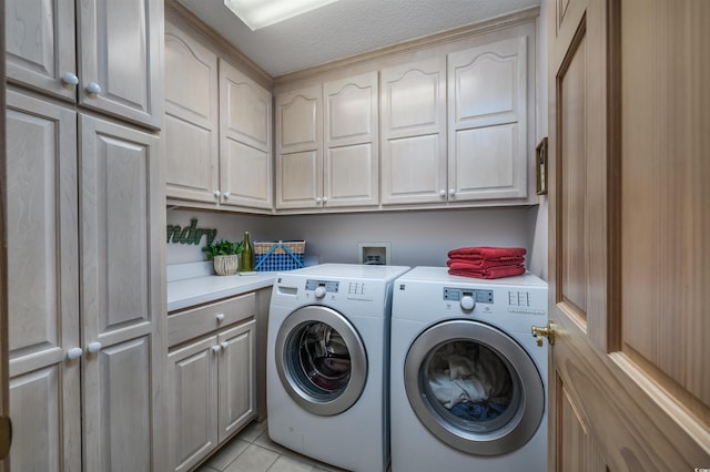 laundry area featuring cabinets, a textured ceiling, washer and dryer, and light tile patterned flooring