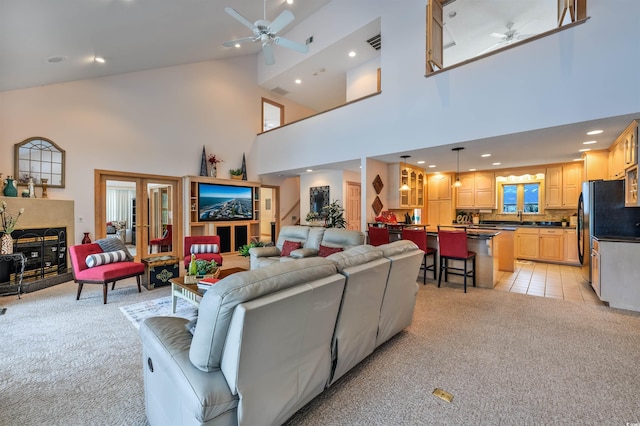 living room with a towering ceiling, light colored carpet, and ceiling fan