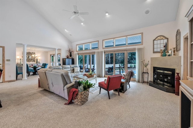 living room featuring ceiling fan, a fireplace, high vaulted ceiling, and light colored carpet