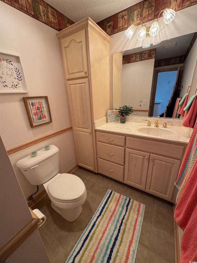 bathroom with vanity, a textured ceiling, tile patterned floors, and toilet