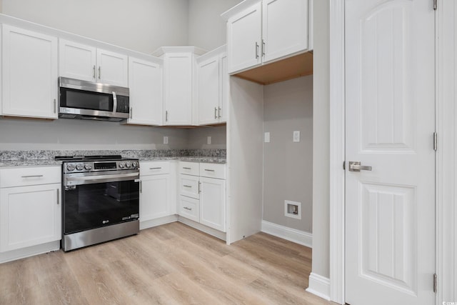 kitchen featuring stainless steel appliances, light stone countertops, light hardwood / wood-style floors, and white cabinets