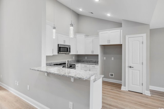 kitchen with white cabinetry, light stone counters, kitchen peninsula, stainless steel appliances, and light wood-type flooring