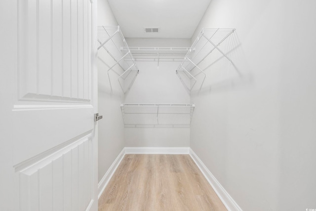 walk in closet with light hardwood / wood-style flooring