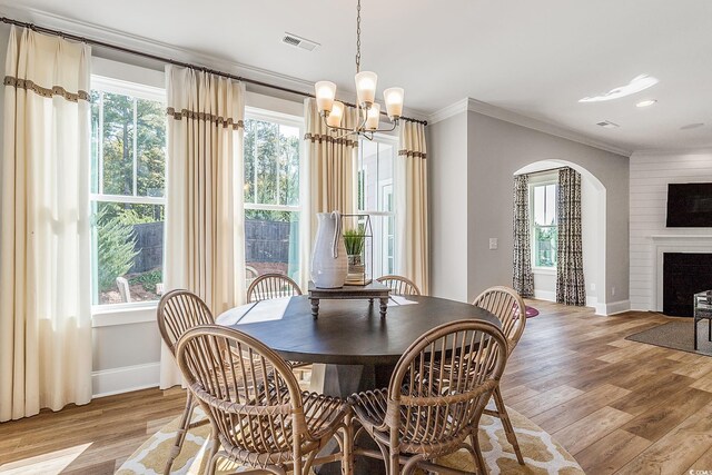 dining area featuring light wood-type flooring, ornamental molding, and a notable chandelier