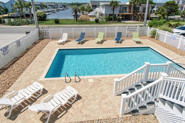 view of pool featuring a patio area and a water view