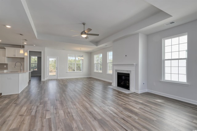 unfurnished living room featuring hardwood / wood-style flooring, a raised ceiling, and a premium fireplace