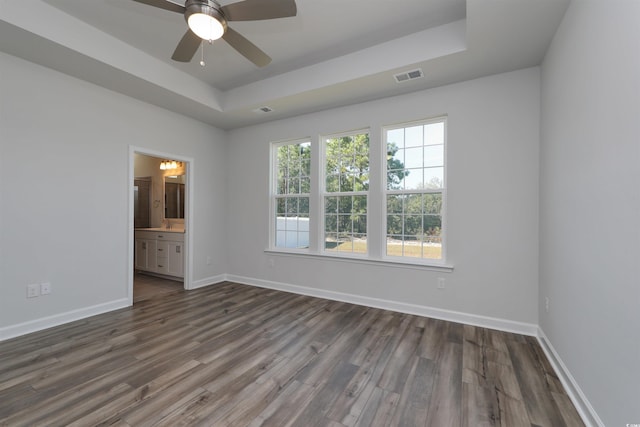 empty room featuring ceiling fan, dark hardwood / wood-style flooring, and a raised ceiling