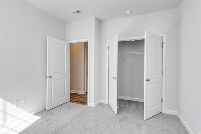 unfurnished bedroom with light carpet and a closet