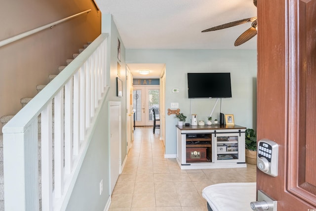 interior space featuring light tile patterned floors, baseboards, stairs, and a ceiling fan