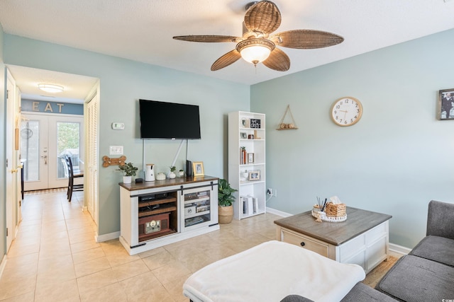 living room featuring light tile patterned floors, ceiling fan, french doors, and baseboards