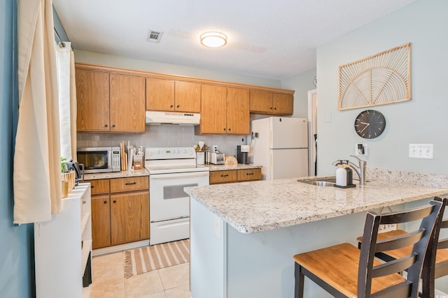 6706 Bryant St Unit B, Myrtle Beach, SC 29572 - kitchen with white appliances, under cabinet range hood, a sink, a breakfast bar, and light tile patterned flooring