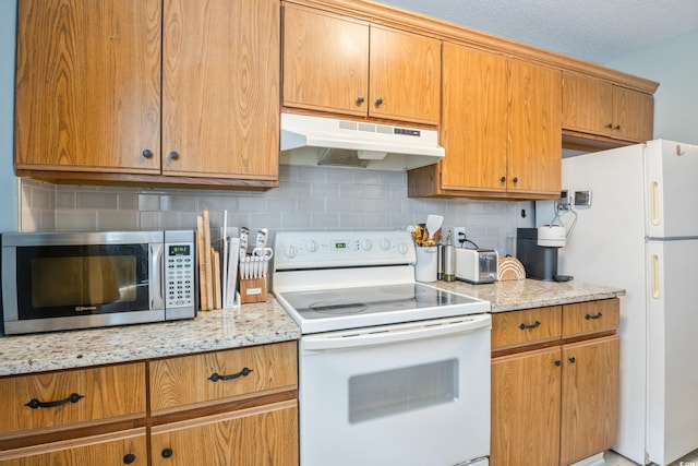 6706 Bryant St Unit B, Myrtle Beach, SC 29572 - kitchen with white appliances, under cabinet range hood, decorative backsplash, and light stone counters