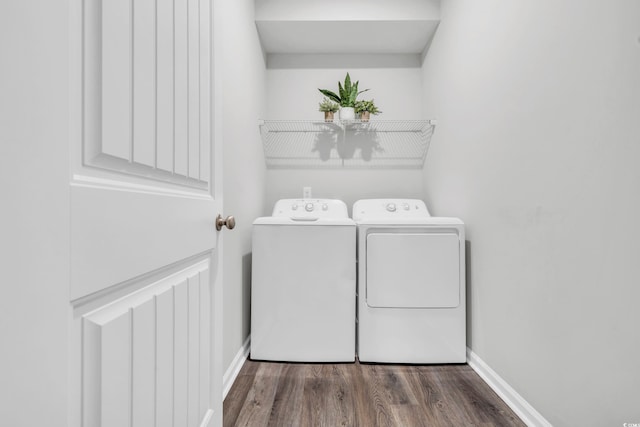 clothes washing area with laundry area, baseboards, washing machine and clothes dryer, and wood finished floors