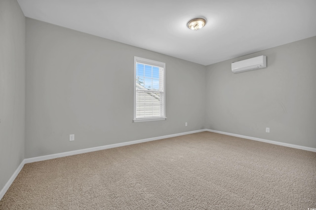 spare room featuring carpet floors, baseboards, and an AC wall unit