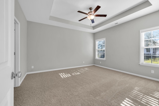 spare room with a healthy amount of sunlight, baseboards, visible vents, and a tray ceiling