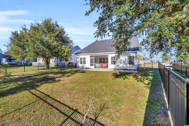 back of property with a yard, a fenced backyard, roof with shingles, and a patio