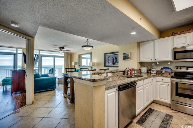 kitchen with sink, kitchen peninsula, ceiling fan, white cabinetry, and stainless steel appliances