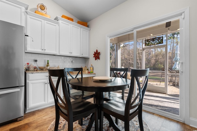 dining room with vaulted ceiling, light hardwood / wood-style floors, and a wealth of natural light