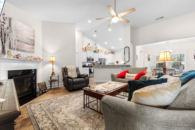 living room featuring wood-type flooring, high vaulted ceiling, and ceiling fan