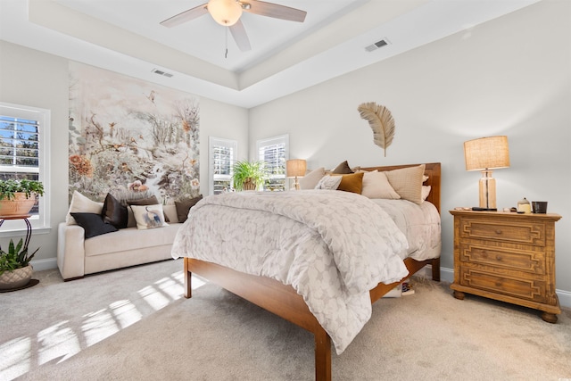 carpeted bedroom featuring a tray ceiling and ceiling fan