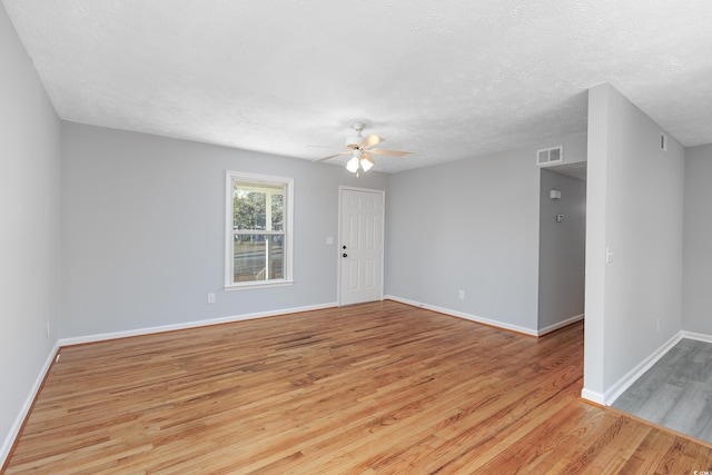 empty room with ceiling fan, a textured ceiling, and light hardwood / wood-style flooring