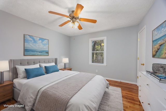 bedroom with ceiling fan, a textured ceiling, and hardwood / wood-style flooring