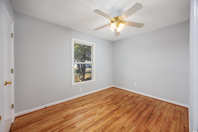 empty room with ceiling fan, light wood-type flooring, and a textured ceiling