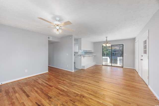 unfurnished living room featuring a textured ceiling, ceiling fan with notable chandelier, and light wood-type flooring