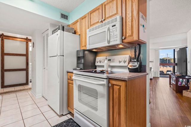 kitchen featuring white appliances, a textured ceiling, and light tile patterned floors