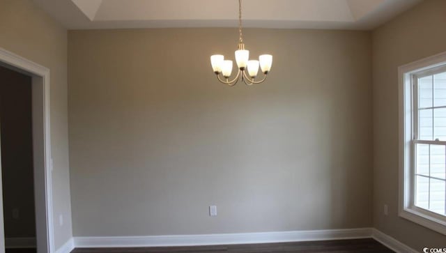 spare room with dark wood-type flooring and an inviting chandelier