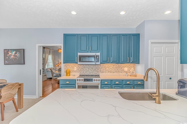 kitchen featuring sink, blue cabinets, light stone countertops, and appliances with stainless steel finishes