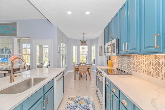 kitchen featuring white appliances, blue cabinetry, light tile patterned floors, sink, and decorative light fixtures