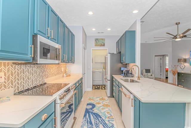 kitchen featuring stainless steel appliances, blue cabinets, light tile patterned flooring, and washer / clothes dryer