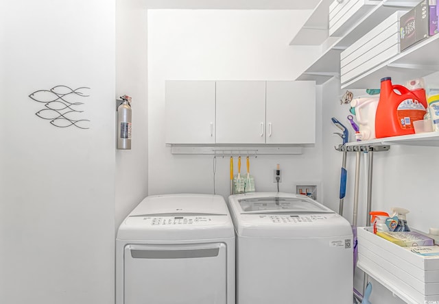 clothes washing area with washer and dryer and cabinets