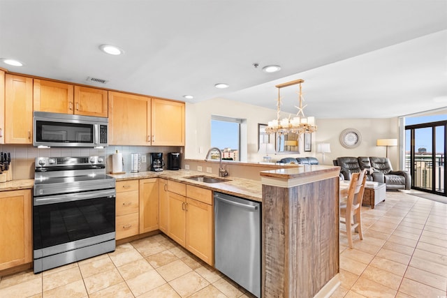 kitchen with sink, light brown cabinets, appliances with stainless steel finishes, kitchen peninsula, and backsplash