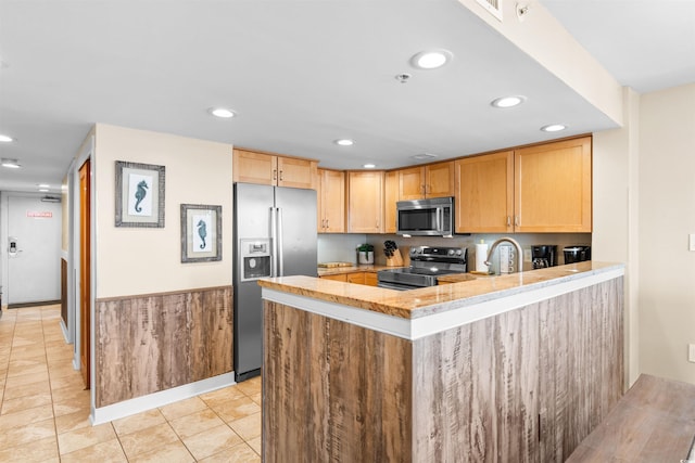 kitchen featuring light tile patterned flooring, sink, kitchen peninsula, stainless steel appliances, and light brown cabinets