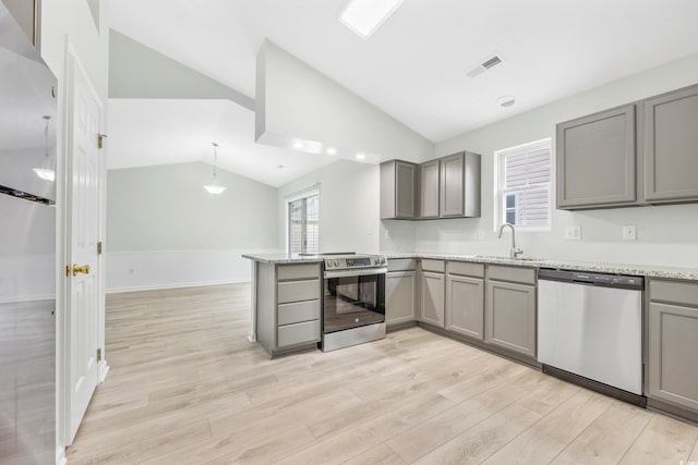 kitchen featuring light wood-type flooring, light stone counters, stainless steel appliances, vaulted ceiling, and gray cabinets