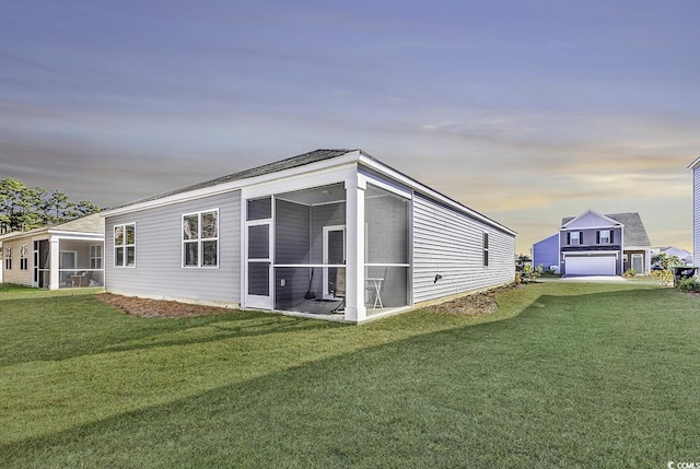 property exterior at dusk with a garage, a lawn, and a sunroom