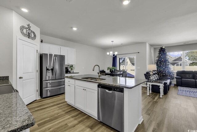 kitchen with appliances with stainless steel finishes, a center island with sink, and white cabinetry