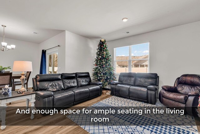 living room featuring wood-type flooring, a wealth of natural light, and an inviting chandelier