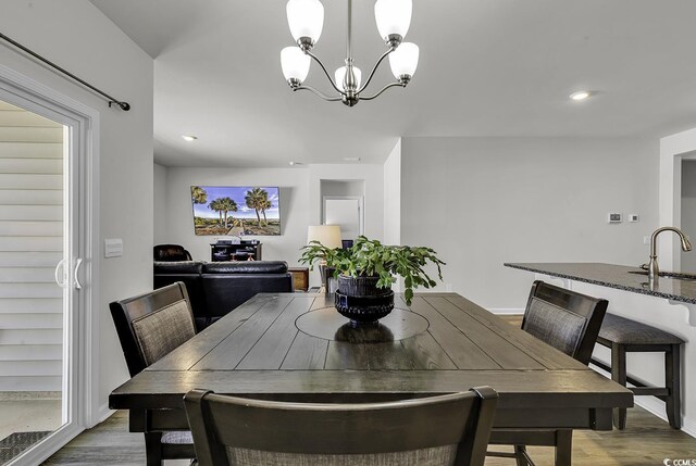 dining space featuring hardwood / wood-style flooring, sink, and a chandelier