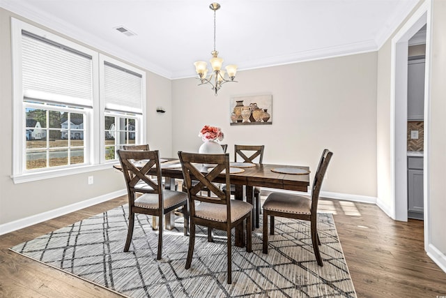 dining space with dark hardwood / wood-style floors, crown molding, and a notable chandelier