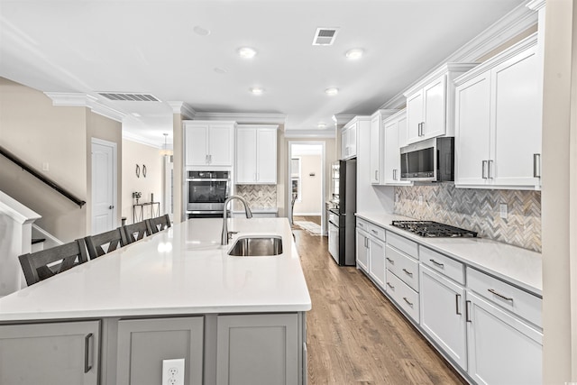 kitchen with a large island, sink, stainless steel appliances, a kitchen bar, and white cabinets