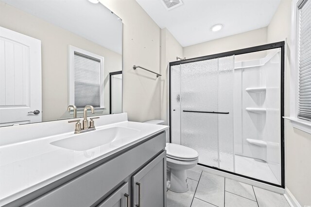 bathroom featuring tile patterned flooring, vanity, an enclosed shower, and toilet