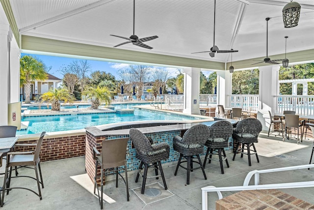 view of swimming pool with ceiling fan, a patio area, and an outdoor bar